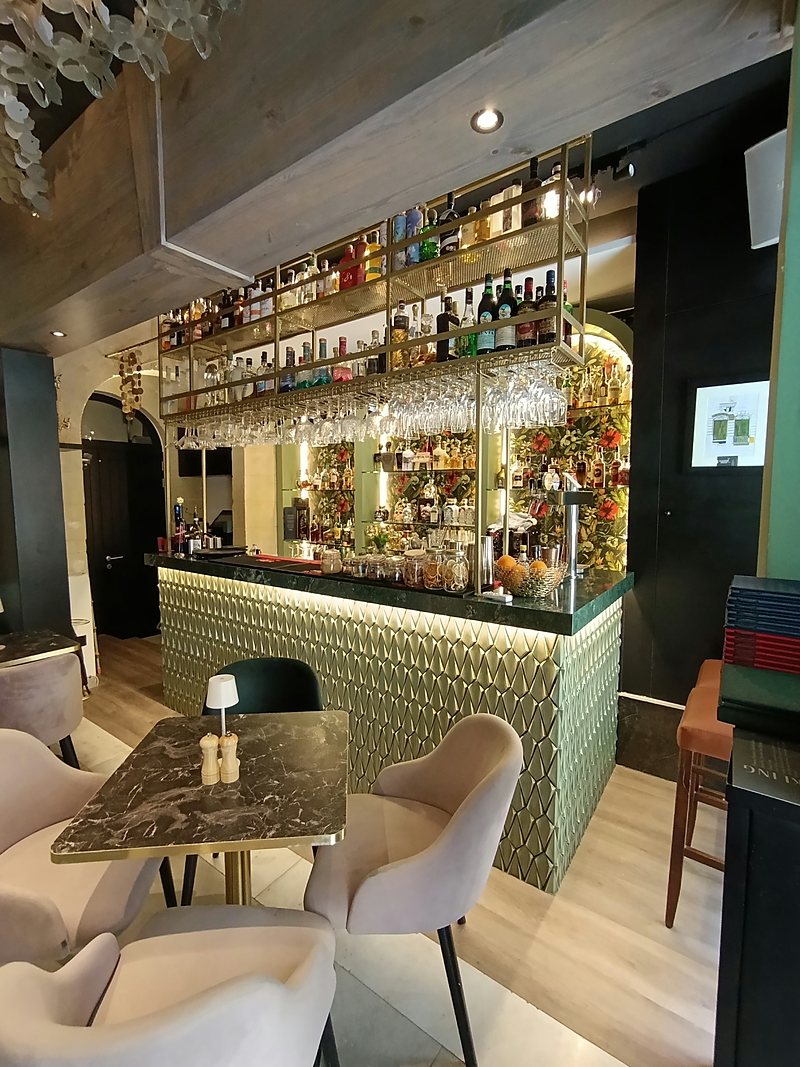 Bar with a green tiled counter, marble table and upholstered chairs