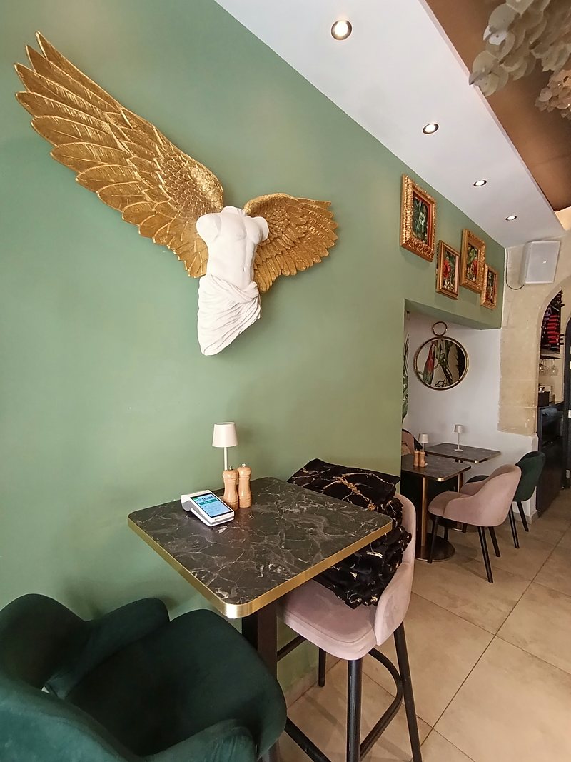 Cafe interior with sage walls and a gilded wall sculpture