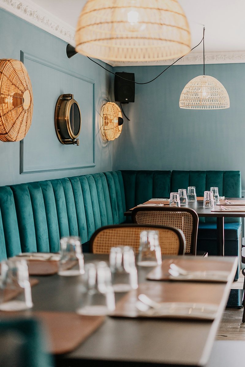 Restaurant with teal banquette seating and rattan chairs