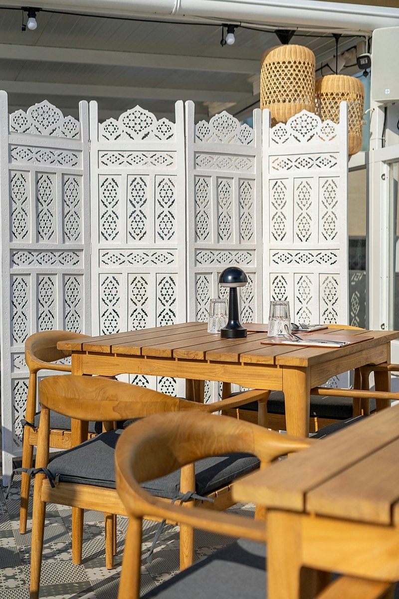 Timber table and cane chairs against carved white fretwork screens