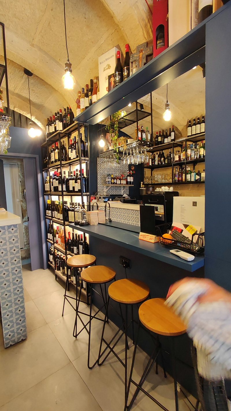 Wine bar under a vaulted stone ceiling with stools at the counter