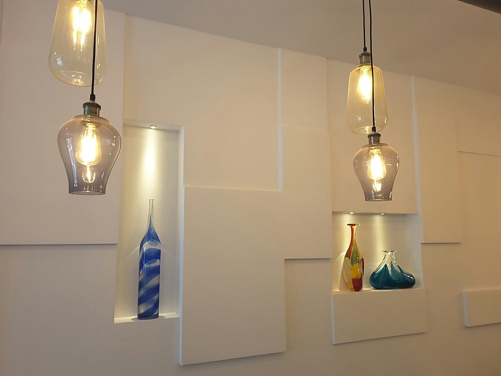 Glass pendants over recessed niches holding coloured glassware